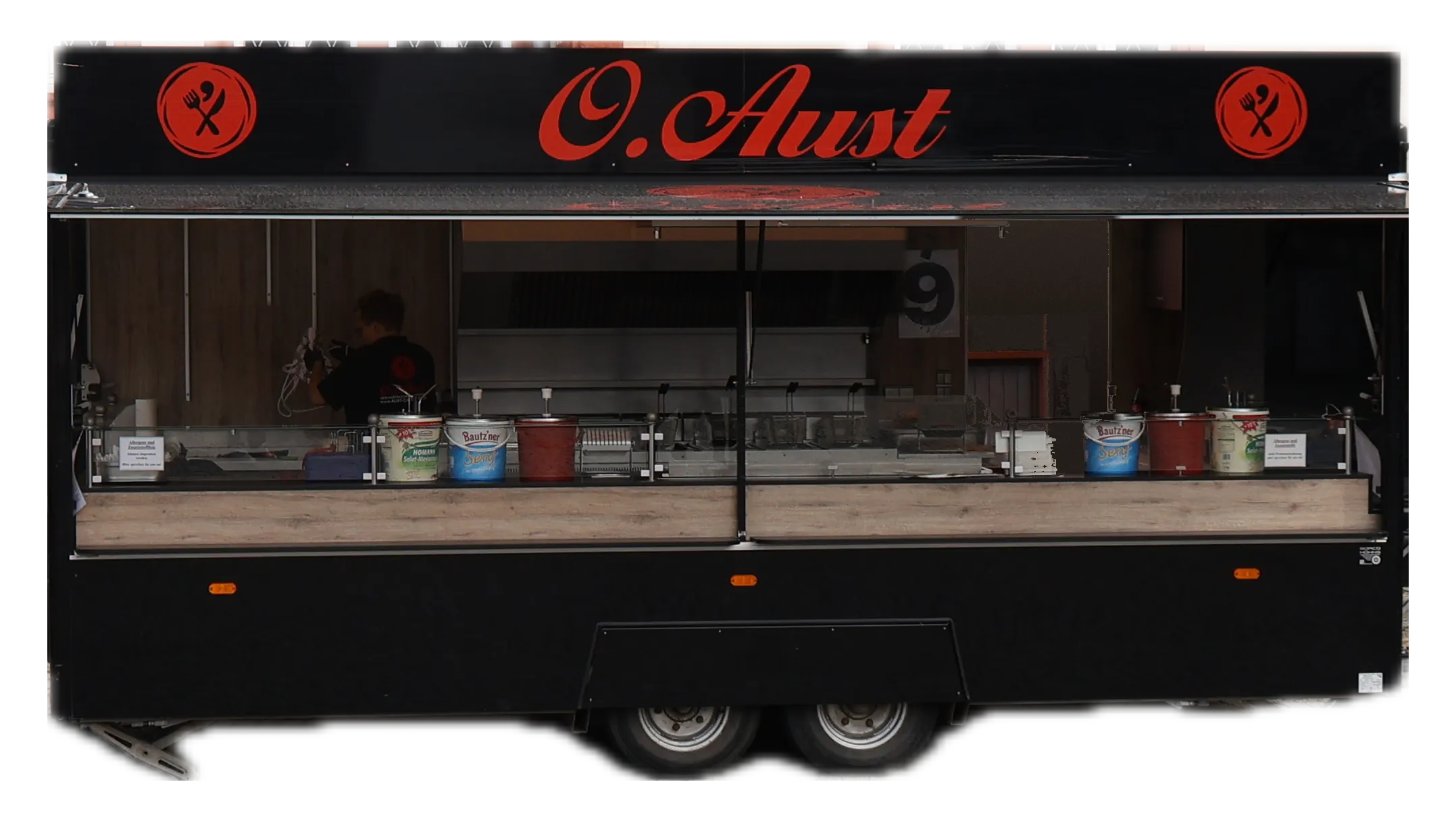 Der große Grillwagen von Aust Catering in der Seitenansicht mit geöffneter Klappe, Ausgabetheke und Grillstation
